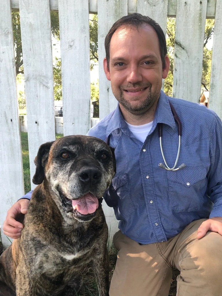 Dr. Allen Baldridge, veterinarian at Bradford Pet Hospital, smiling with a senior brindle Mastiff mix